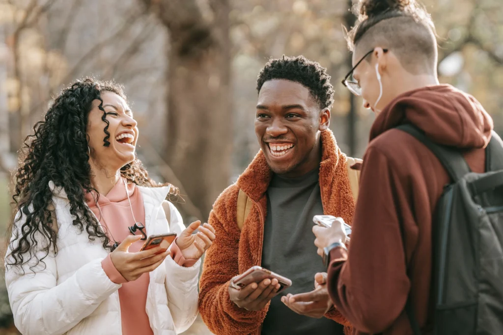 Dark Social & the Cosy Web: Youth Culture's New Home Three Gen Z friends sharing content and laughing together while using their smartphones outdoors